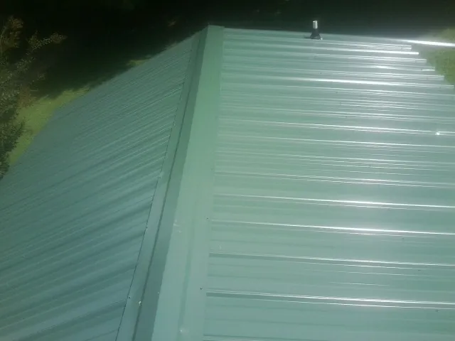New green metal panels meeting at the ridge of a roof — Flat Roof Repair work by our crew in Sapphire