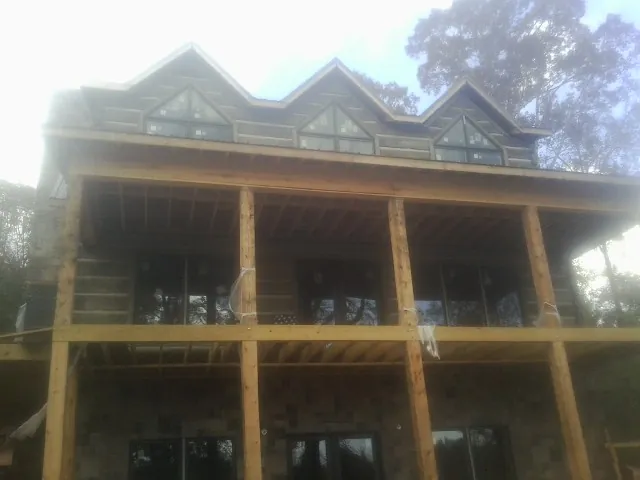 Dormers and porch framing on a large log home under construction — Roof Coating work by our crew in Sapphire