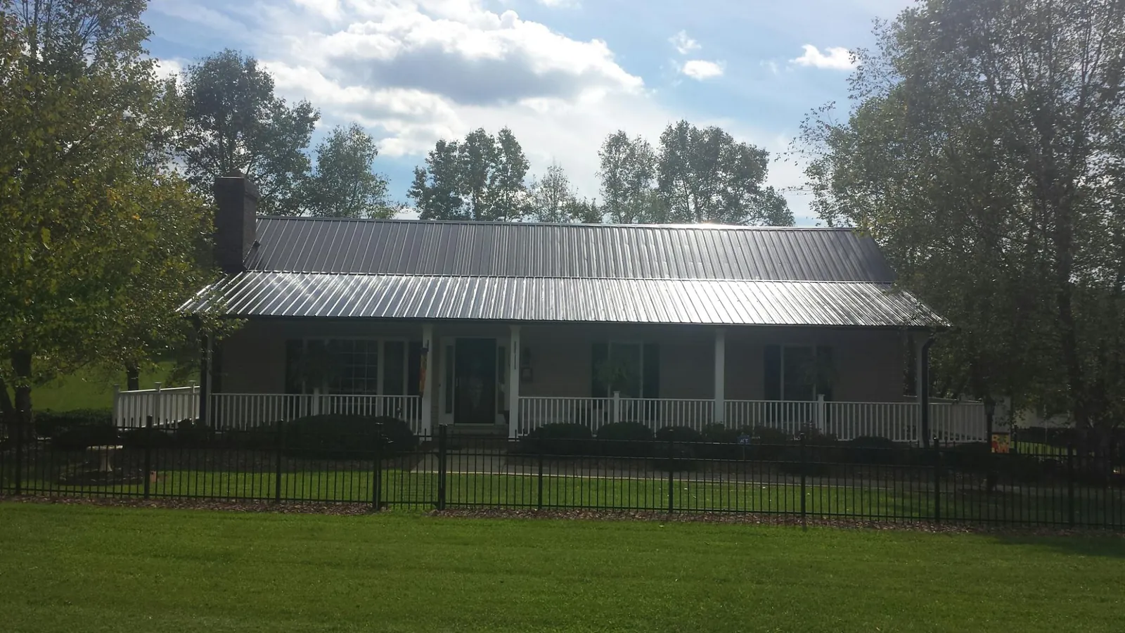 Gray metal roof on a brick ranch with a full width front porch — Gutter Guard Installation work by our crew in Sapphire