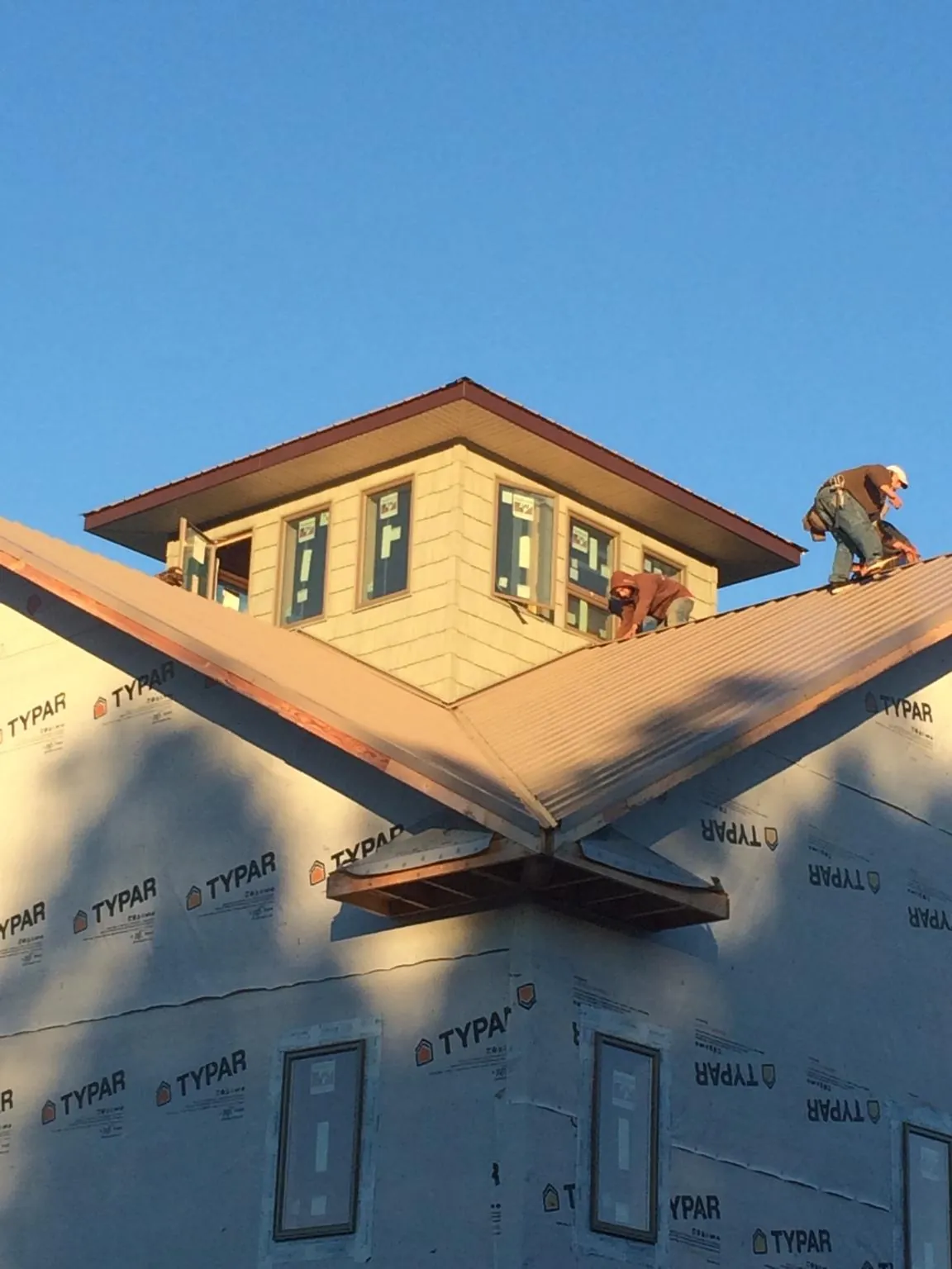 Roofers working around a rooftop cupola on a new metal roof at sunset — Roof Waterproofing in Sapphire by Roofing Brothers